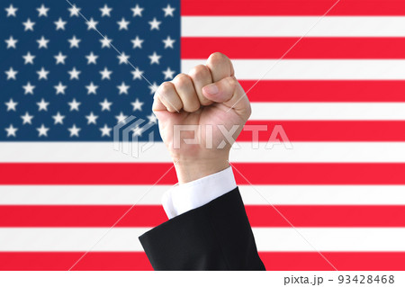 アメリカ国旗の前でガッツポーズをするビジネスマンの手元 93428468