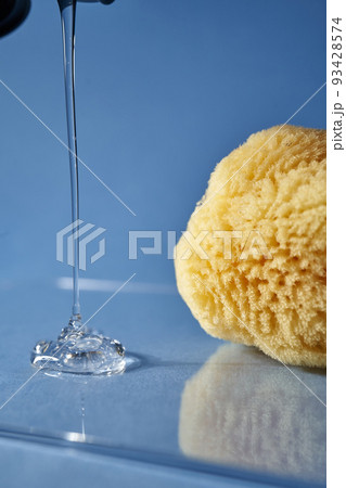 A natural sponge and a drop of gel or shampoo on a blue background. A natural sponge and a drop of gel or shampoo on a blue background. 93428574