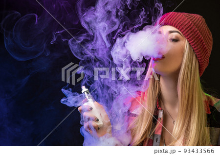 Vaping girl. Young hipster woman vape e-cig on studio on black background. Hip-hop style. Close up. 93433566