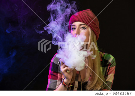 Vaping girl. Young hipster woman vape e-cig on studio on black background. Hip-hop style. Close up. 93433567
