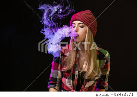 Vaping girl. Young hipster woman vape e-cig on studio on black background. Hip-hop style. Close up. 93433571