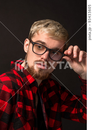 Image of attractive young bearded hipster man wearing glasses dressed in shirt in a cage isolated over black background. 93433605