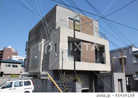 青空に映えるアースカラーのキューブ型の都市型3階建ての穴あきレンガブロックスクーリンがある美しい邸宅 93434139