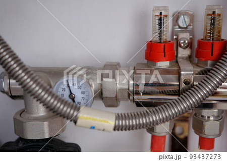 Heating system manifold valves for heat flooring and water supply in a country house. Pipes collector in a building under construction Heating system manifold valves for heat flooring and water supply in a country house. Pipes collector in a building under construction 93437273