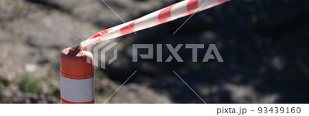 Red and white tape stretched in front of danger zone closeup 93439160