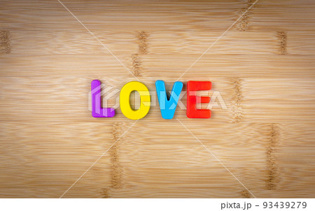 The word love is laid out of multicolored letters on a table background with a wood texture. Concept. Game. Word. Love 93439279