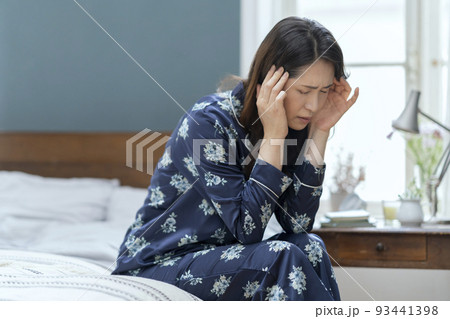ベッドに座って頭を抱えるパジャマ姿のアラフィフの女性 ベッドに座って頭を抱えるパジャマ姿のアラフィフの女性 93441398