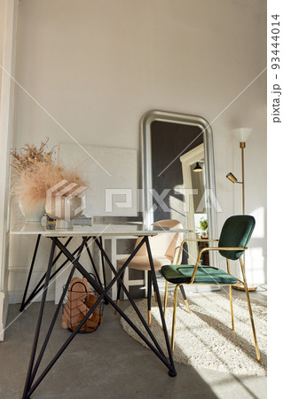Interior of light room with table and chairs decorated with vases and mirror 93444014