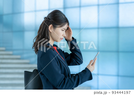スマホを見ながら落ち込む若い女性 スマホを見ながら落ち込む若い女性 93444197