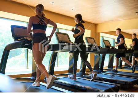 Rear view of group of people running on treadmills during sports training in gym 93445139