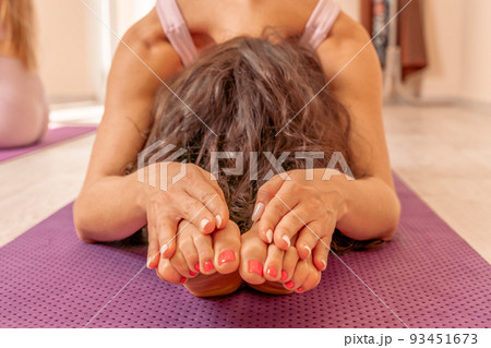 Middle aged woman looks good, practicing yoga, fitness, sports, training, woman doing exercises. She is wearing a pink top and leggings. The concept of grace and beauty of the body 93451673