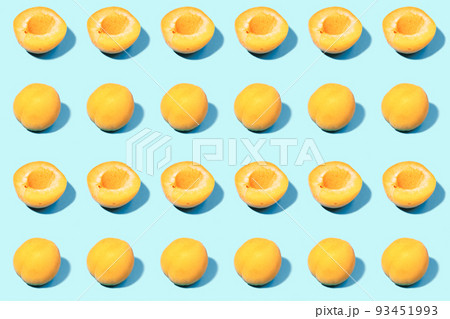 Summer pattern of ripe apricots on a blue background - fruit harvest concept - whole apricots and halves 93451993