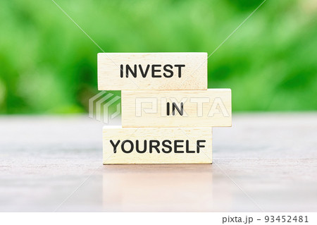 Investing in yourself. Text on wooden blocks on a green background 93452481