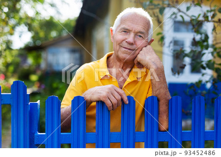 Portrait of pensive elderly man at fence of his country house in village Portrait of pensive elderly man at fence of his country house in village 93452486