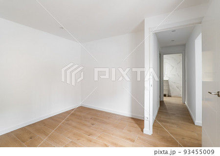 Empty room with laminate flooring and newly painted white wall in refurbished apartment with corridor leading to bathroom. Repair and construction concept. Empty room with laminate flooring and newly painted white wall in refurbished apartment with corridor leading to bathroom. Repair and construction concept. 93455009