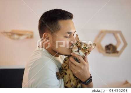 Young man in t shirt holding a cat. 93456293