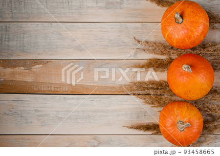 Autumn minimalistic background. Ripe pumpkins and ears of wheat on wooden boards. Harvest and Thanksgiving concept. 93458665