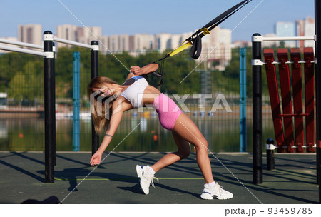 Sports woman with short hair doing crossfit push ups with fitness straps outside. Sports woman with short hair doing crossfit push ups with fitness straps outside. 93459785