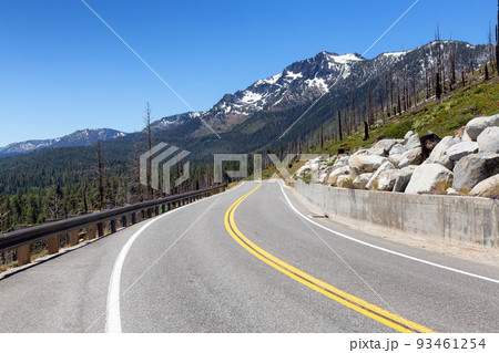 Scenic Road surrounded by Trees and Mountains on a Sunny Day. Scenic Road surrounded by Trees and Mountains on a Sunny Day. 93461254