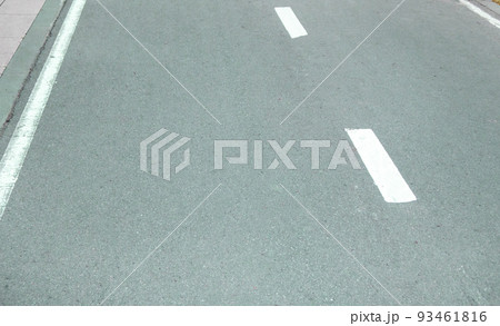 Close-up of an asphalt road with an intermittent marking line. Selective focus Close-up of an asphalt road with an intermittent marking line. Selective focus 93461816