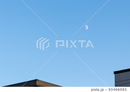 住宅地の上の青空に浮かぶ半月 93466093