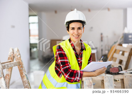 Positive woman builder checking project documentation Positive woman builder checking project documentation 93466390