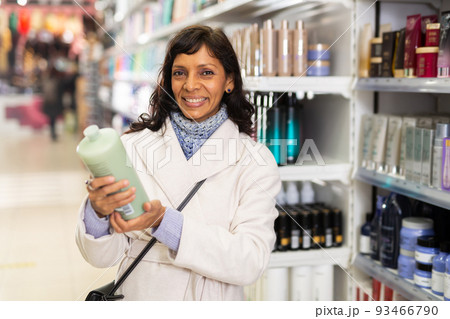 Hispanic woman choosing hair care treatments in cosmetics store 93466790