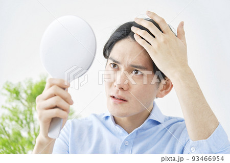 自宅でハンドミラーを持って髪の毛を見る男性 自宅でハンドミラーを持って髪の毛を見る男性 93466954