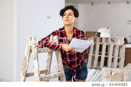 Woman designer checking documents during repair works 93466985