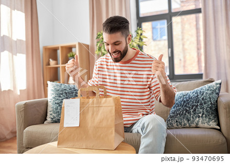 smiling man unpacking takeaway food at home smiling man unpacking takeaway food at home 93470695