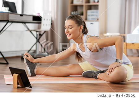 teenage girl with tablet pc exercising at home 93470950