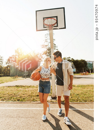 happy couple with ball on basketball playground 93470974