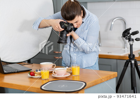 food photographer with camera working in kitchen 93471641