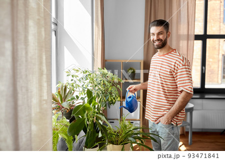 happy smiling man watering flowers at home 93471841