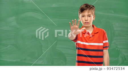 student boy showing stop gesture over chalkboard student boy showing stop gesture over chalkboard 93472534