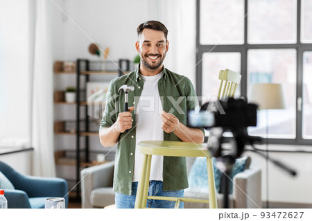 male blogger with hammer showing chair renovation 93472627