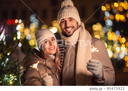 happy couple with sparklers over christmas lights 93473322