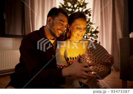 happy couple opening christmas gift at home happy couple opening christmas gift at home 93473387