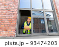 male builder with clipboard looking out window 93474203