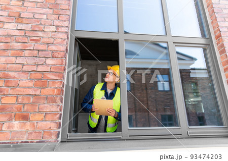 male builder with clipboard looking out window male builder with clipboard looking out window 93474203