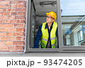 smiling male builder in helmet looking out window 93474205