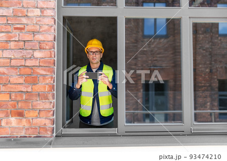 builder with smartphone taking picture at window 93474210