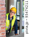 male builder in helmet looking out window 93474211