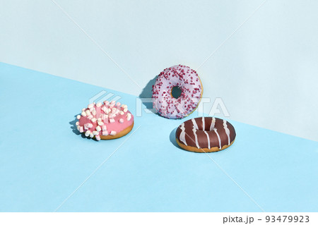 Three sweet tasty donuts in caramel and chocolate icing, on a two-color background Three sweet tasty donuts in caramel and chocolate icing, on a two-color background 93479923