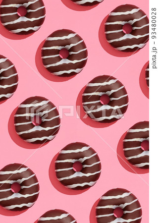 Food design with tasty chocolate glazed donut with white strips on coral pink pastel background top view pattern Food design with tasty chocolate glazed donut with white strips on coral pink pastel background top view pattern 93480028