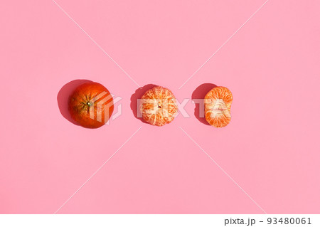 Food design. Composition of whole mandarin, peeled mandarin and half of peeled mandarin on pink coral background Food design. Composition of whole mandarin, peeled mandarin and half of peeled mandarin on pink coral background 93480061