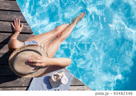 Woman on wooden deck near swimming pool 93482346