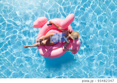 Woman relaxing on pink flamingo inflatable ring 93482347
