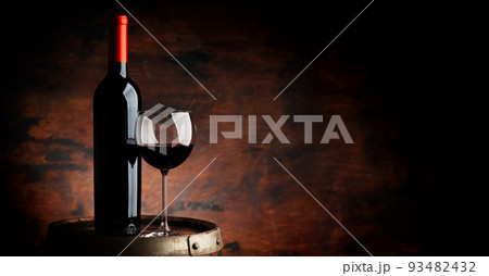 Red wine glass and wine bottle on old wooden barrel 93482432