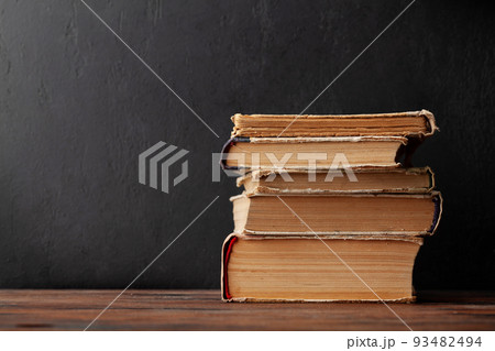 Old books on wooden table and blackboard Old books on wooden table and blackboard 93482494